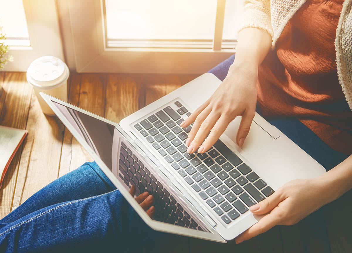 Woman person working on the laptop while sitting at the window.